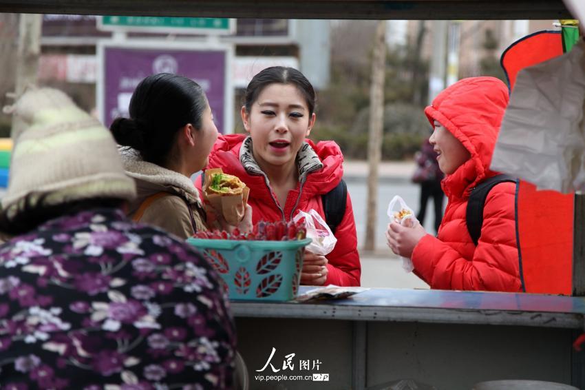 2014年2月17日，山東濱州，背著大包小包的藝考考生在濱州學(xué)院考點外買飯。