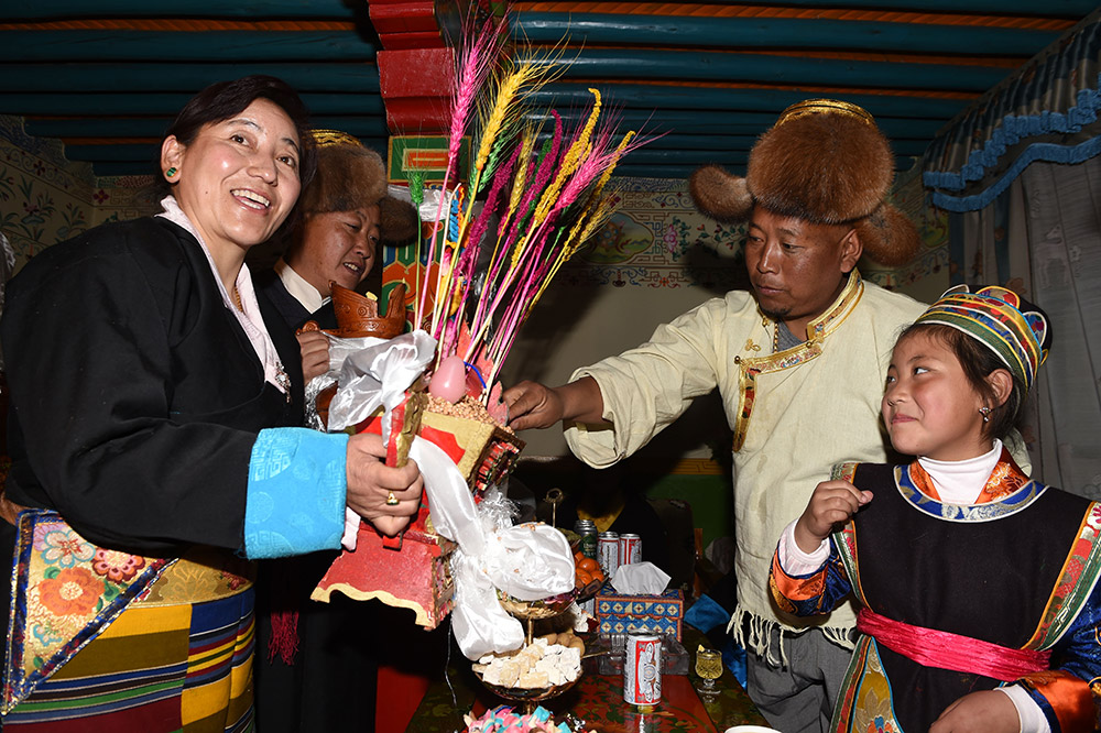 2月27日，拉薩市城關(guān)區(qū)阿壩林卡社區(qū)居民央拉（左）向鄰居敬獻(xiàn)“切瑪”。